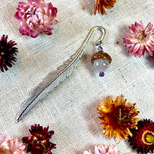 Load image into Gallery viewer, a close up of flowers and a feather on a table
